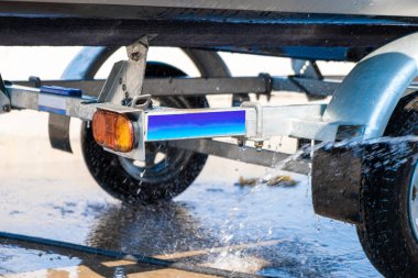 Bir adam denize açıldıktan sonra kauçuk hortum teknesini yıkar. Tekneden dökülen su damlaları..