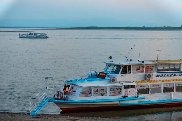 Khabarovsk, Rusia - 17 de mayo de 2019: Puesta de sol en el terraplén del río Amur. Buque de pasajeros en el río Amur al atardecer . — Foto de Stock