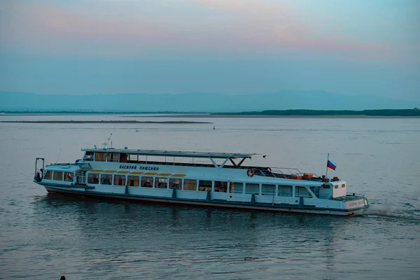 Khabarovsk, Rússia - 17 de maio de 2019: Pôr do sol no dique do rio Amur. Navio de passageiros no rio Amur durante o pôr do sol . — Fotografia de Stock