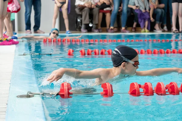 Khabarovsk, Russia - May, 19, 2019: children swimming freestyle. Indoor swimming pool with clear blue water. — Stock Photo, Image