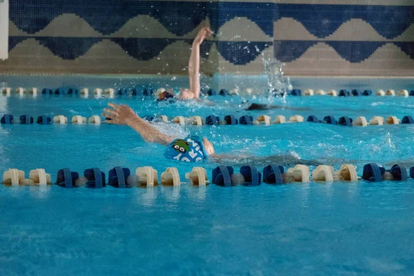 Khabarovsk, Rusya - 19 Mayıs 2019: Sırtüstü yüzen çocuklar. Berrak mavi su ile kapalı yüzme havuzu. — Stok fotoğraf