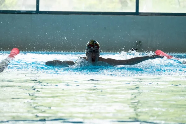 Khabarovsk, Russia - May, 19, 2019: children swimming Butterfly. Indoor swimming pool with clear blue water. — Stock Photo, Image