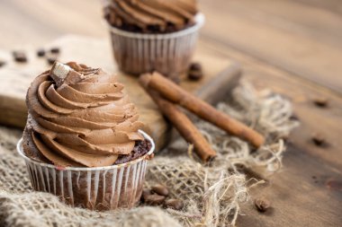 ahşap arka plan üzerinde kakao krema, tarçın ve kahve ile kahverengi cupcakes