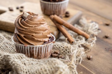 ahşap arka plan üzerinde kakao krema, tarçın ve kahve ile kahverengi cupcakes