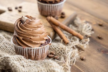 ahşap arka plan üzerinde kakao krema, tarçın ve kahve ile kahverengi cupcakes