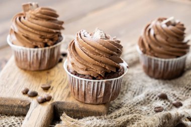 ahşap arka plan üzerinde kakao krema, tarçın ve kahve ile kahverengi cupcakes
