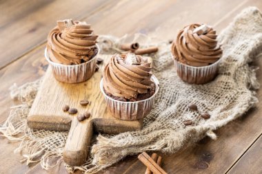 ahşap arka plan üzerinde kakao krema, tarçın ve kahve ile kahverengi cupcakes