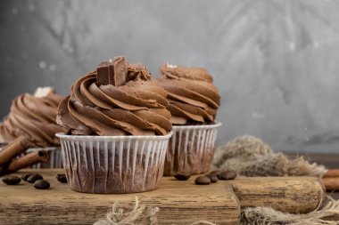 ahşap arka plan üzerinde kakao krema, tarçın ve kahve ile kahverengi cupcakes