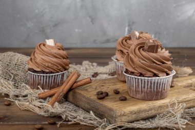 ahşap arka plan üzerinde kakao krema, tarçın ve kahve ile kahverengi cupcakes
