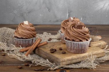 ahşap arka plan üzerinde kakao krema, tarçın ve kahve ile kahverengi cupcakes