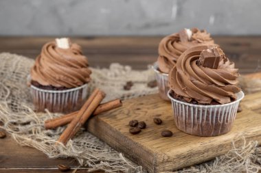 ahşap arka plan üzerinde kakao krema, tarçın ve kahve ile kahverengi cupcakes