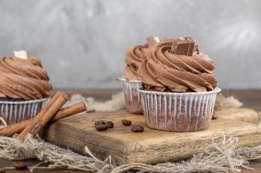ahşap arka plan üzerinde kakao krema, tarçın ve kahve ile kahverengi cupcakes
