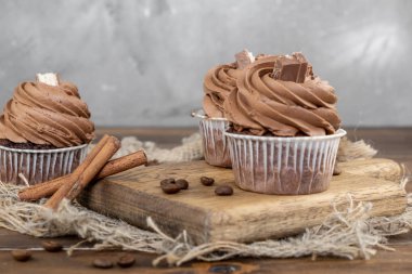 ahşap arka plan üzerinde kakao krema, tarçın ve kahve ile kahverengi cupcakes