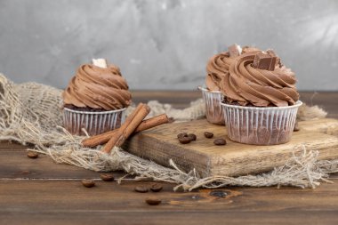ahşap arka plan üzerinde kakao krema, tarçın ve kahve ile kahverengi cupcakes