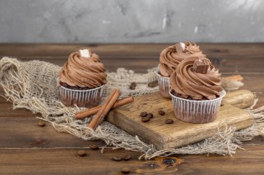 ahşap arka plan üzerinde kakao krema, tarçın ve kahve ile kahverengi cupcakes
