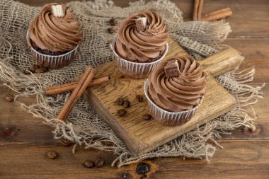 ahşap arka plan üzerinde kakao krema, tarçın ve kahve ile kahverengi cupcakes