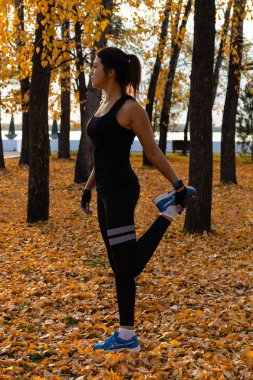 Khabarovsk, Rusya - Eki 07, 2018: Gün batımı ve Amur nehrine karşı doğada spor egzersizleri yapan spor kıyafetleri içinde çekici bir kadın, jimnastiği seviyor, bacaklarını yoğurunuyor. Aktif genç kız tr