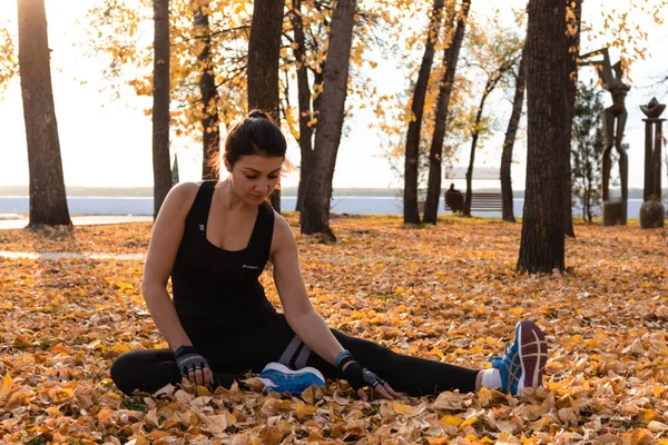 Χαμπάροφσκ, Ρωσία-07 Οκτ, 2018: νέα αθλητική γυναίκα που τεντώνει και ετοιμάζεται να τρέξει. Ελκυστική γυναίκα σε αθλητικά ρούχα κάνει αθλητικές ασκήσεις στη φύση, στο χαλί των φύλλων του φθινοπώρου, αγαπά — Φωτογραφία Αρχείου