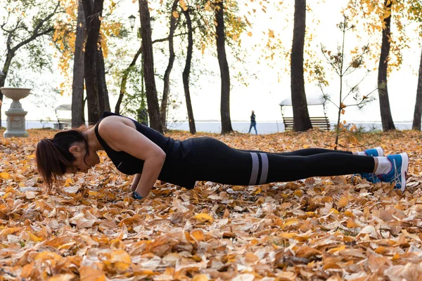 Khabarovsk, Russia - Oct 07, 2018: Young sportswoman stretching and preparing to run. Attractive woman in sports clothes doing sports exercises in nature, on the carpet of autumn leaves, loves — Stock Photo, Image