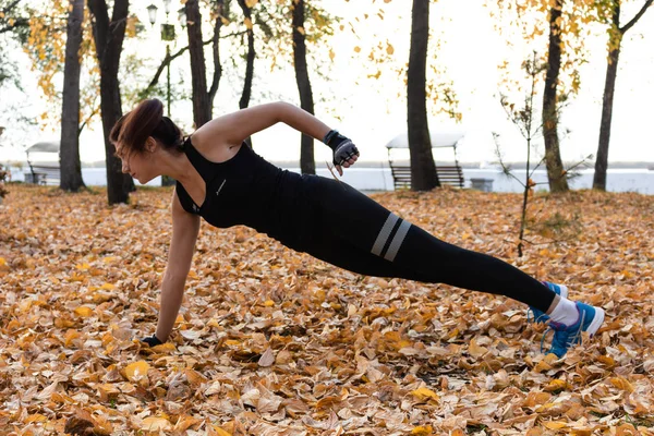 Khabarovsk, Russia - Oct 07, 2018: Young sportswoman stretching and preparing to run. Attractive woman in sports clothes doing sports exercises in nature, on the carpet of autumn leaves, loves — Stock Photo, Image