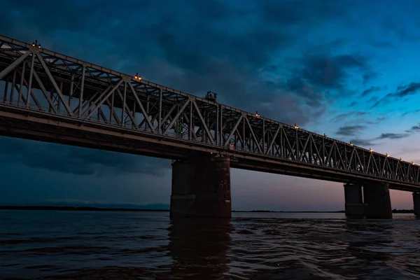 Brücke über den Amur bei Sonnenuntergang. Russland. Chabarowsk. Foto aus der Mitte des Flusses. — Stockfoto