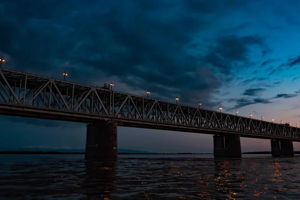 Ponte sobre o rio Amur ao pôr-do-sol. A Rússia. Khabarovsk. Foto do meio do rio . — Fotografia de Stock