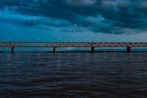 Brücke über den Amur bei Sonnenuntergang. Russland. Chabarowsk. Foto aus der Mitte des Flusses. — Stockfoto