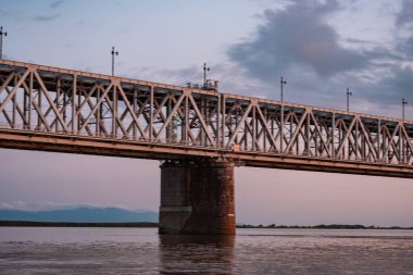 Gün batımında Amur nehri üzerinde köprü. Rusya. Khabarovsk. Nehrin ortasından fotoğraf.