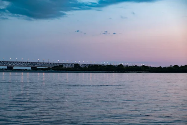 Most nad rzeką Amur o zachodzie słońca. Rosja. Chabarowsk. Zdjęcie z połowy rzeki. — Zdjęcie stockowe