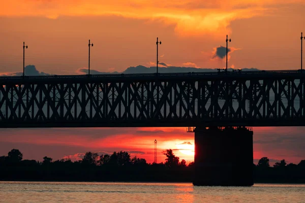 Most nad rzeką Amur o zachodzie słońca. Rosja. Chabarowsk. Zdjęcie z połowy rzeki. — Zdjęcie stockowe
