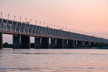 Gün batımında Amur nehri üzerinde köprü. Rusya. Khabarovsk. Nehrin ortasından fotoğraf.
