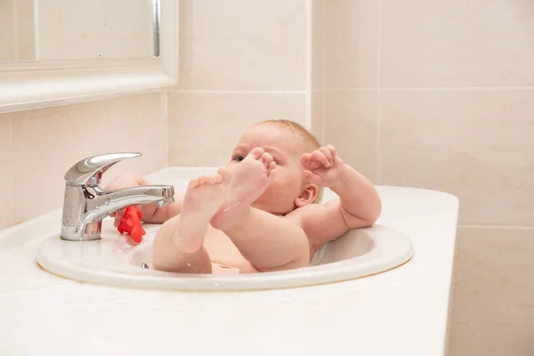 En glad lille pige bader i hotellets håndvask . - Stock-foto