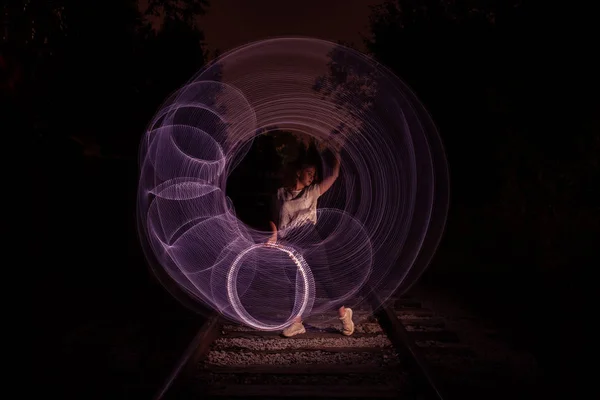 Young girl surrounded by frozen light. Drawing with light. Long exposure. Artistic abstraction. Freezelight — Stock Photo, Image