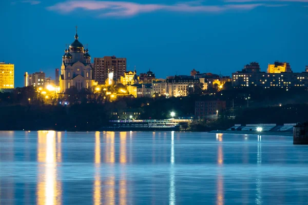 Ночной вид на город Хабаровск с реки Амур. Голубое ночное небо. Ночной город освещается светильниками. — стоковое фото