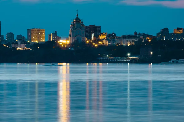 Night View of the city of Khabarovsk from the Amur river. Blue night sky. The night city is brightly lit with lanterns.