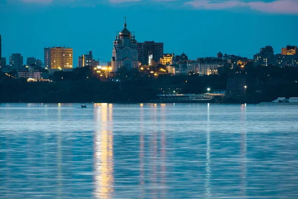 Vue de nuit de la ville de Khabarovsk depuis la rivière Amour. Ciel nocturne bleu. La ville nocturne est éclairée par des lanternes. — Photo