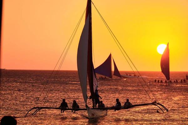 Boracay, Filipíny - 23. ledna 2020: Západ slunce na ostrově Boracay. Plachtění a další tradiční lodě s turisty na moři na pozadí zapadajícího slunce. — Stock fotografie