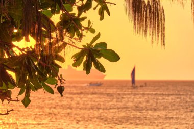 Boracay, Filipinler - 23 Ocak 2020 Boracay Adası 'nda gün batımı. Yelkencilik ve turistlerle dolu diğer geleneksel tekneler batan güneşin arka planına karşı. Arka planda ünlü Milenyum yolcu gemisi