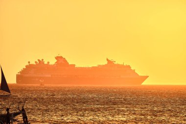 Boracay, Filipinler - 23 Ocak 2020 Boracay Adası 'nda gün batımı. Yelkencilik ve turistlerle dolu diğer geleneksel tekneler batan güneşin arka planına karşı. Arka planda ünlü Milenyum yolcu gemisi