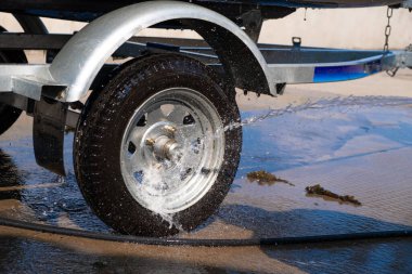 Bir adam denize açıldıktan sonra kauçuk hortum teknesini yıkar. Tekneden dökülen su damlaları.