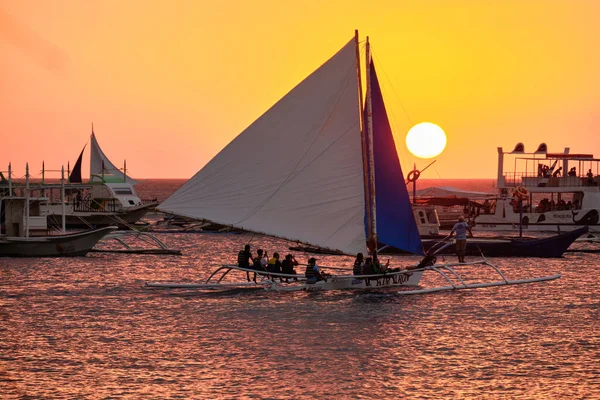 Boracay, Filipíny - 23. ledna 2020: Západ slunce na ostrově Boracay. Plachtění a další tradiční lodě s turisty na moři na pozadí zapadajícího slunce. — Stock fotografie