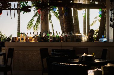Boracay, Filipinler - 26 Ocak 2020: Barda duran şişelerin arka planında gün batımı. Güneş, şişelerin parlak camından geçer. Ekran koruyucu için arkaplan resmi.