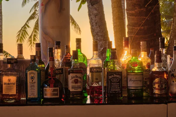 Boracay, Filipinler - 29 Ocak 2020: Barda duran şişelerin arka planında gün batımı. Güneş, şişelerin parlak camından geçer. Ekran koruyucu için arkaplan resmi.