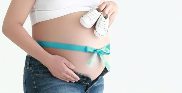 Tummy de mulher grávida com fita azul e sapatos de bebê — Fotografia de Stock