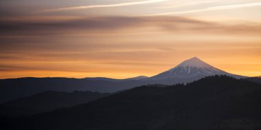 Güneş ufukta aşağı kayıyor ve Mt. Mcloughlin Cascade aralıktaki çevresinde zengin doymuş portakal rengi değiştirmez