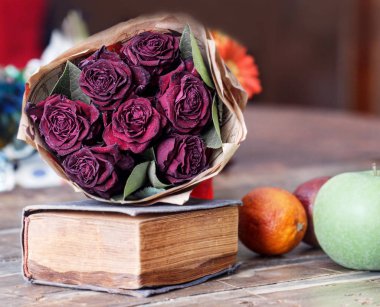 Natürmort kuru kırmızı gül ve meyve ile eski kitap