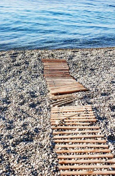 Wooden path to sea on pebble beach