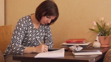 Bir kadın bir tükenmez kalem ile el yazısı metin bir defterde yazıyor..