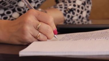 Bir kadın el yazısı metin bir defterde yazıyor.