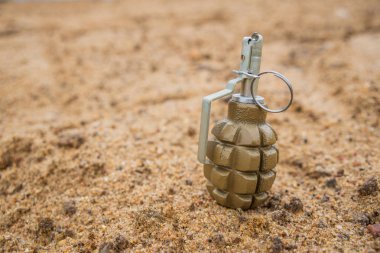 Hand grenade on sand background